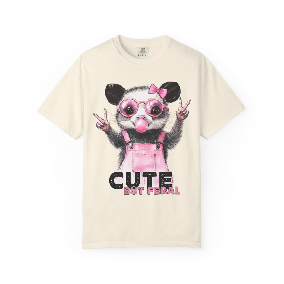 Cute But Feral, Possum in Pink Bibs - Comfort Colors | Trendy Women's T-Shirt. Direct to Garment. Printed & Shipped in the USA. Unisex Sizes.