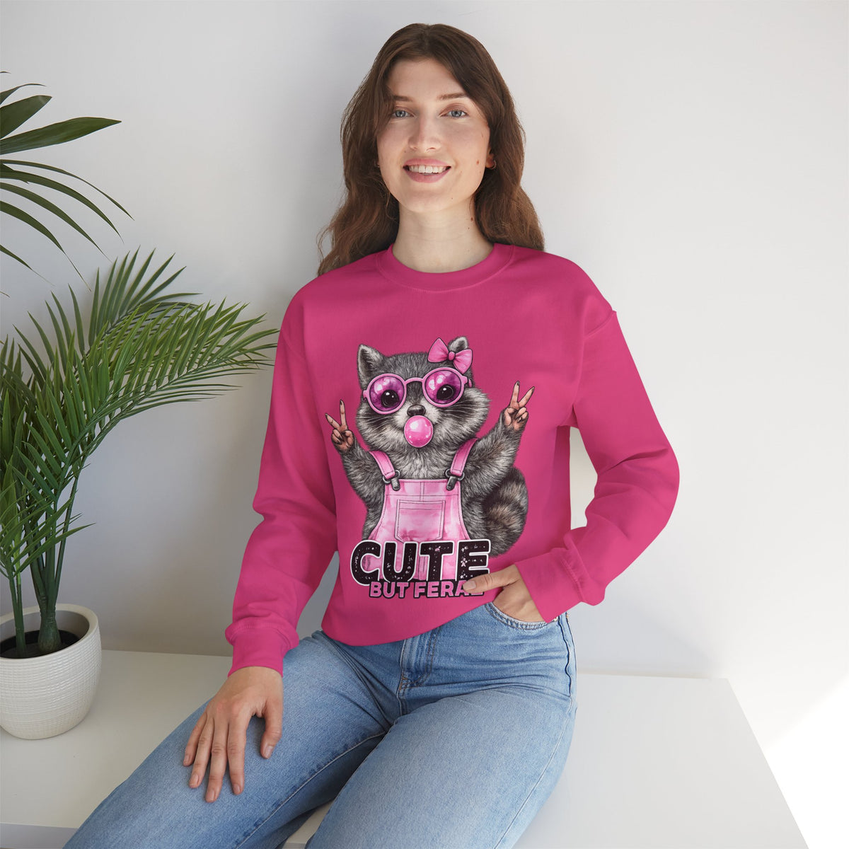 Cute But Feral, Raccoon in Pink Bibs – Gildan Heavy Blend | Trendy Women’s Soft Sweatshirt. Direct to Garment. Printed & Shipped in the USA. Unisex Sizes.