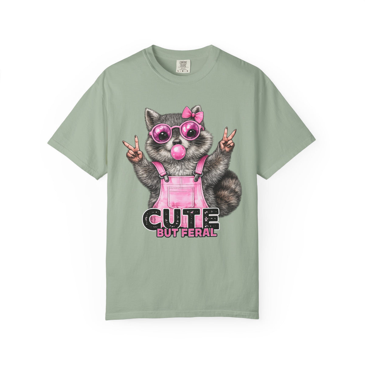 Cute But Feral, Raccoon in Pink Bibs - Comfort Colors | Trendy Women's T-Shirt. Direct to Garment. Printed & Shipped in the USA. Unisex Sizes.