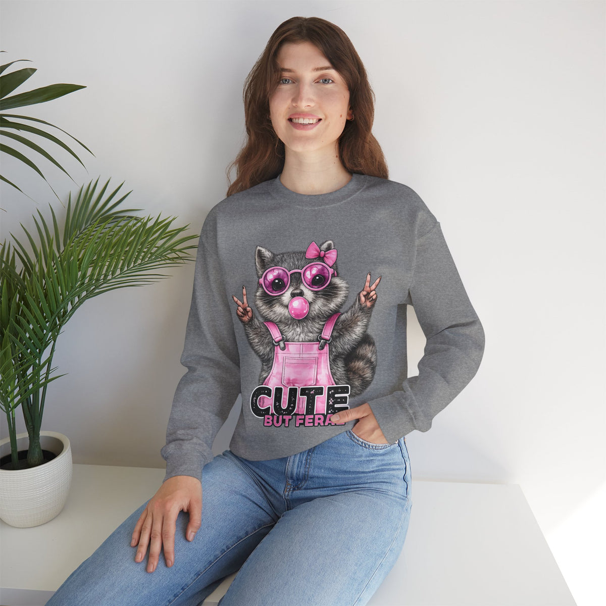 Cute But Feral, Raccoon in Pink Bibs – Gildan Heavy Blend | Trendy Women’s Soft Sweatshirt. Direct to Garment. Printed & Shipped in the USA. Unisex Sizes.