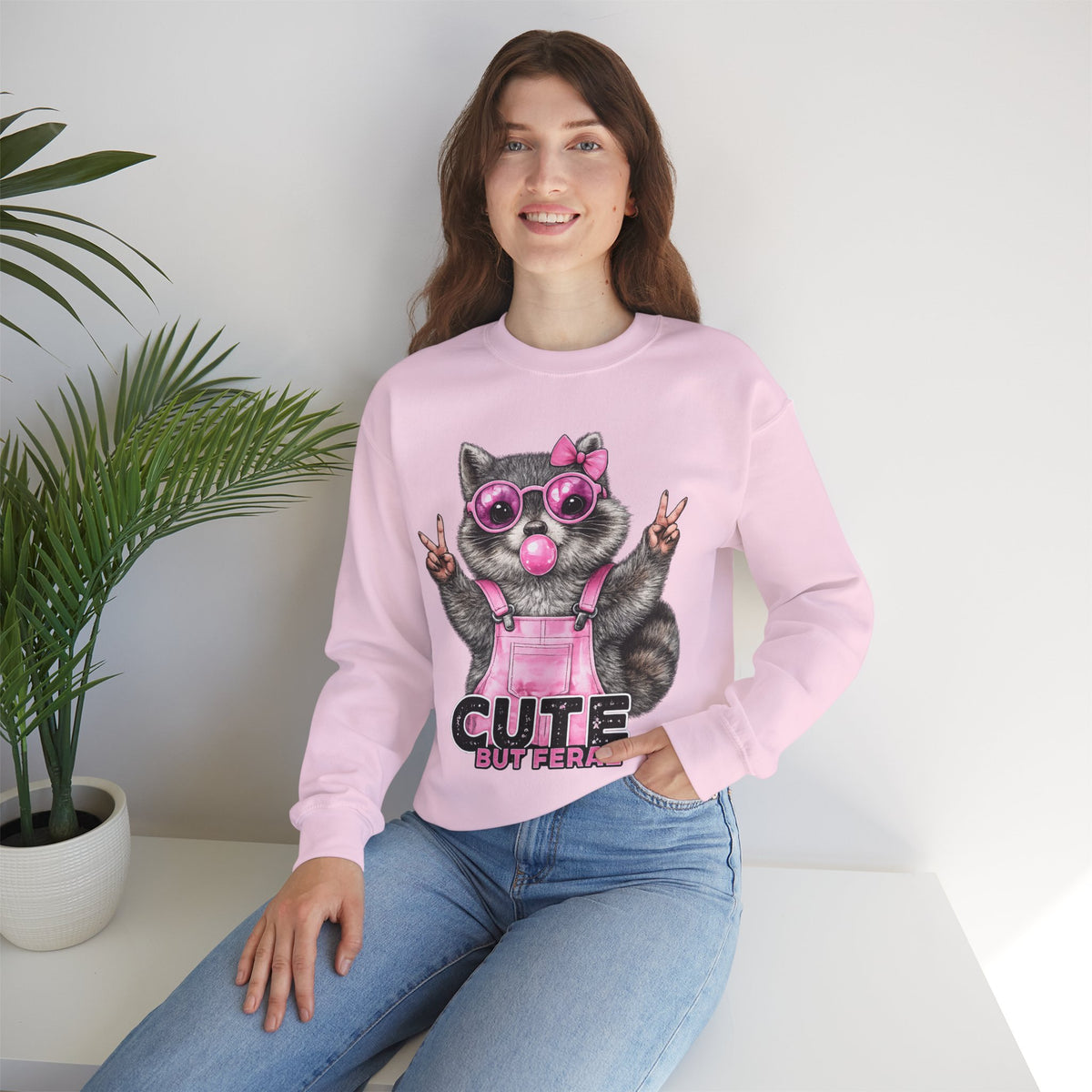 Cute But Feral, Raccoon in Pink Bibs – Gildan Heavy Blend | Trendy Women’s Soft Sweatshirt. Direct to Garment. Printed & Shipped in the USA. Unisex Sizes.