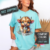 Coffee Addict Highland Cow Drinking Iced Coffee - Comfort Colors | Trendy Women's T-Shirt. Direct to Garment. Printed & Shipped in the USA. Unisex Sizes.