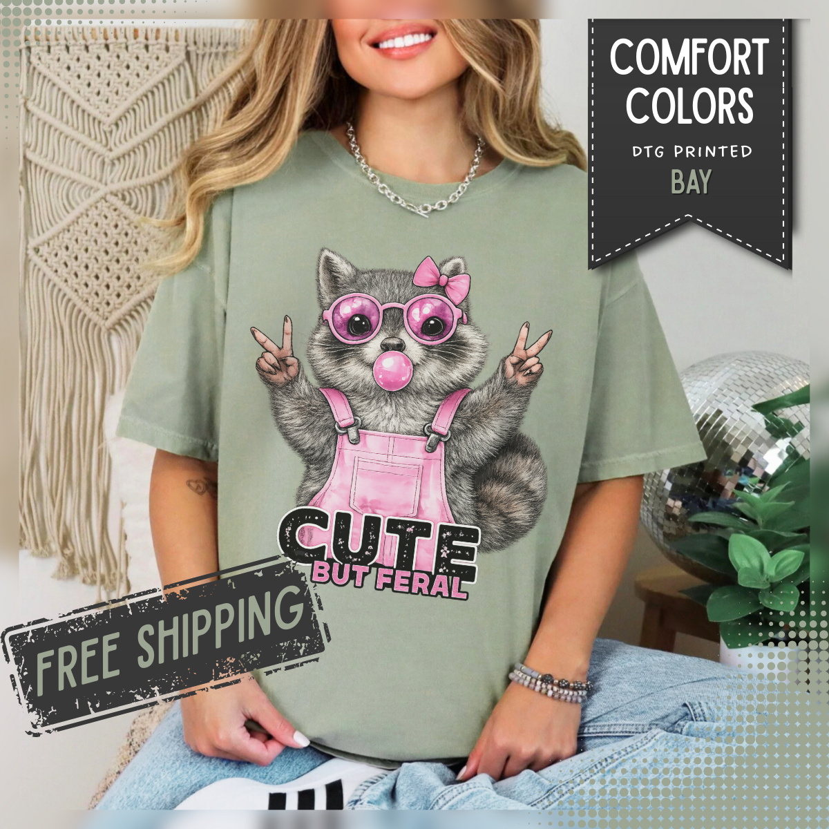 Cute But Feral, Raccoon in Pink Bibs - Comfort Colors | Trendy Women's T-Shirt. Direct to Garment. Printed & Shipped in the USA. Unisex Sizes.